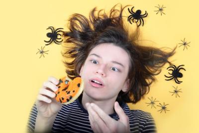 A Guy with Frightened Look Enjoying an Orange Doughnut Surrounded by Crawling Black Spiders on a Yellow Background – Free Stock Photo, Download for Free