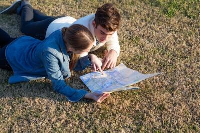 Young Couple Lying on the Grass While Checking a Map – Free Stock Photo, Download Free