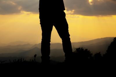 Silhouette of a Relaxed Man on a Hill at Sunset – Free to Download