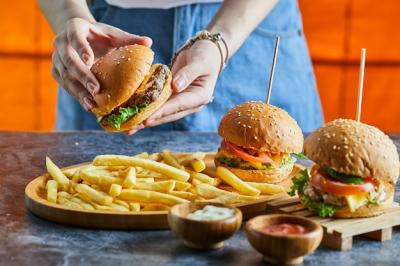 A Woman Holding a Cheeseburger with Fries and Condiments – Free Stock Photo Download