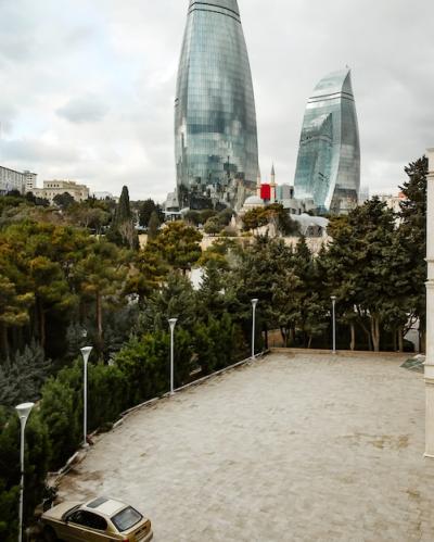 Parking Lot Surrounded by Trees with City Skyscrapers View – Free Download