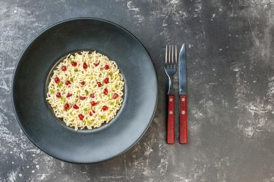 Top View of Asian Ramen Noodles on Black Round Plate with Fork and Knife – Free Download