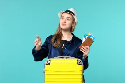 Young Woman Ready for Her Journey, Holding Tickets Against a Blue Background – Free Stock Photo, Download for Free