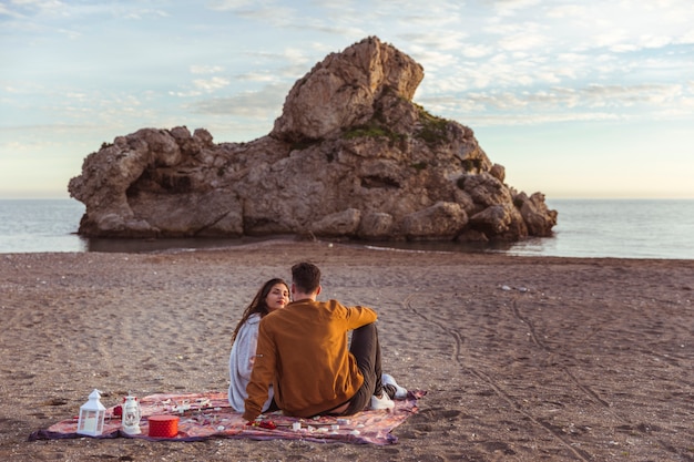 Couple Sitting on a Coverlet at the Seashore – Free Download