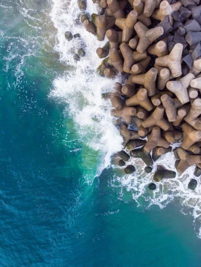 Vertical Overhead Aerial Shot of a Wavy Blue Sea Against the Rocks – Free Download