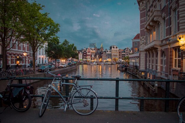 Bicycle by Canal Against City Buildings – Free Download