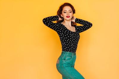 Sensual Red-Haired Girl in Green Pants Dancing Against a Yellow Background – Free Download