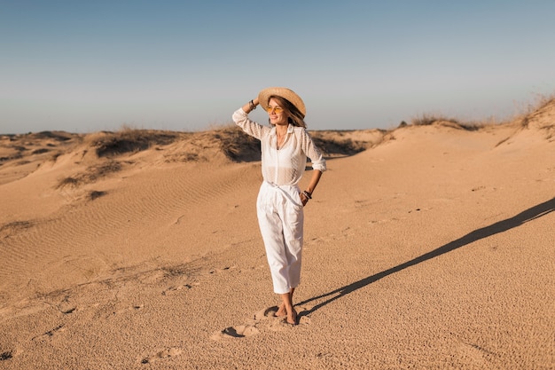 Beautiful Woman in White Outfit Walking in Desert Sand at Sunset – Free Download