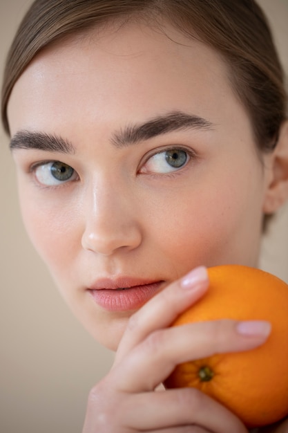 Beautiful Woman with Clear Skin Holding Orange Fruit – Free Download