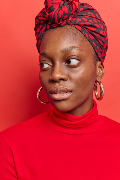 Thoughtful Woman in Turtleneck and Headscarf Against Bright Red Background – Free Download