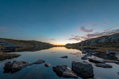 Calm Lake Surrounded by Rocks Under a Sunset Sky – Free Stock Photo for Download