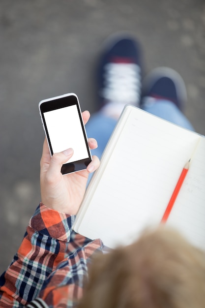 Student Holding Smartphone Against Open Copybook – Free Download