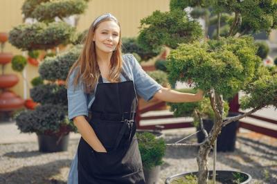 Woman in a Black Apron Working in a Greenhouse – Free Download