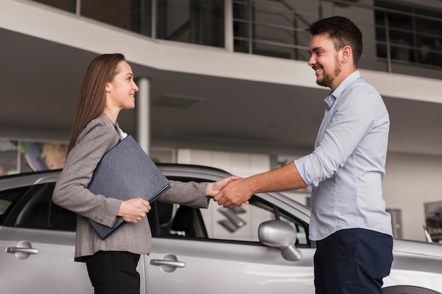 Lateral View of a Young Man Shaking Hands with a Car Dealer – Free Download