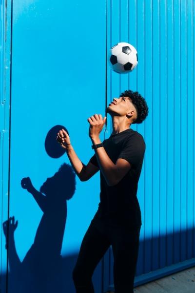 Male Athlete Training with Soccer Ball Against Cyan Wall – Free Download