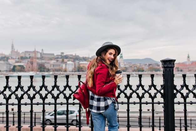 Excited Brunette Lady in Checkered Shirt Enjoying Scenic River Views – Free Download