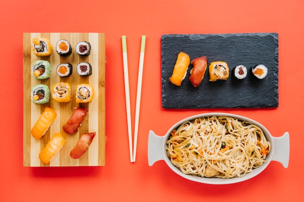 Noodles and Sushi with Chopsticks on Red Background – Free Download