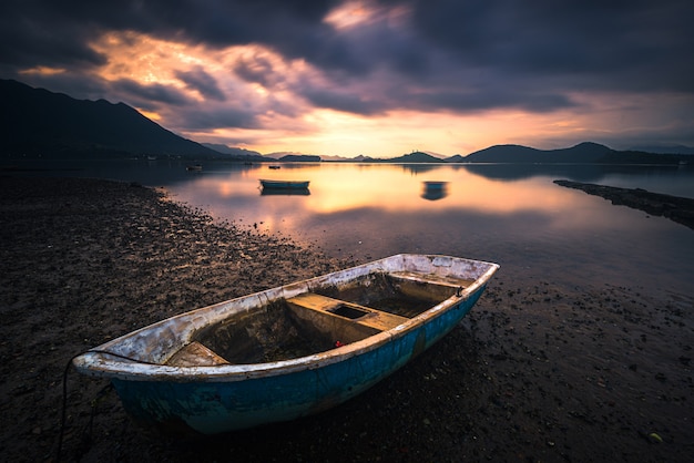 Scenic Lake View with Wooden Rowboat and Dramatic Clouds – Free Download