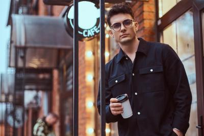 A Young Handsome Man with Takeaway Coffee at an Outdoor Cafe – Free Download