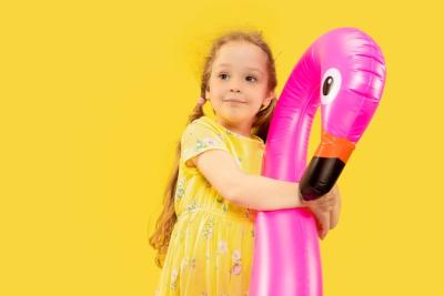 Happy Little Girl with Pink Flamingo on Yellow Background – Free Stock Photo for Download