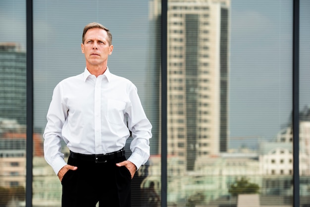 Businessman with Hands in Pockets Near Glass Building – Free Stock Photo for Download