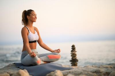 Smiling Woman Meditating on a Rock by the Sea – Free Download