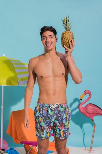 Young Man Sticking Tongue Out and Holding Pineapple – Free Download