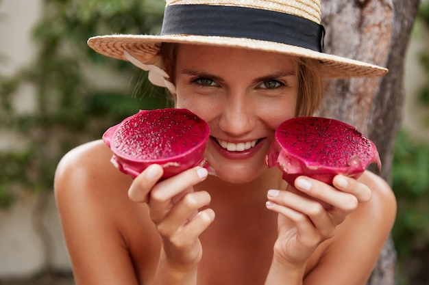 Happy Young Woman in Hat Holding Dragon Fruit – Free Download