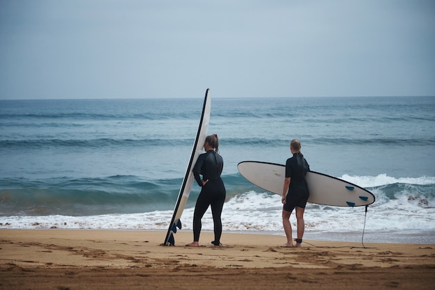 Two Women in Wetsuits with Surfboards Preparing for Summer Waves – Free Stock Photo for Download