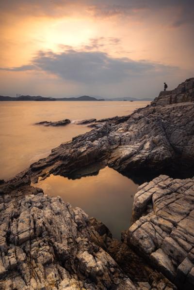 Stunning Sunset Over Water and Cliffs in Cloudy Sky – Free to Download