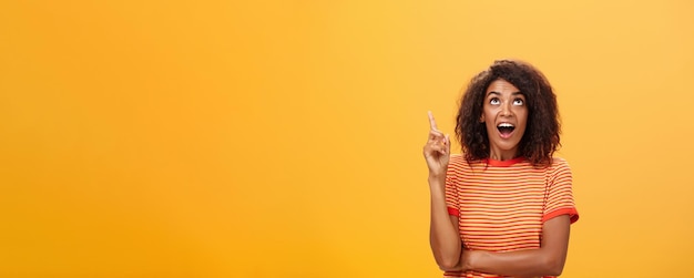 Curious Dark-Skinned Female Pointing Up in Striped T-Shirt – Free Download