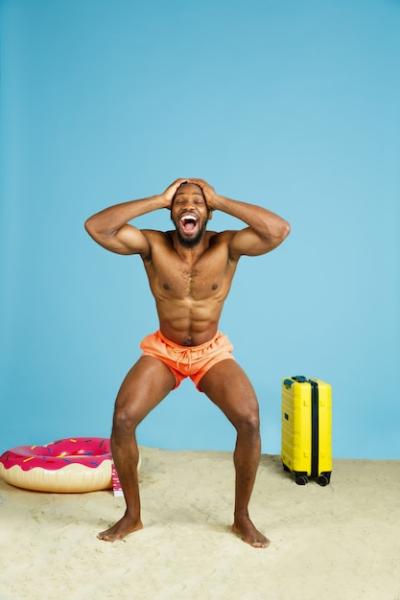 Shocked Happy Young Man with Beach Ring as Donut on Blue Studio Background – Free Stock Photo for Download