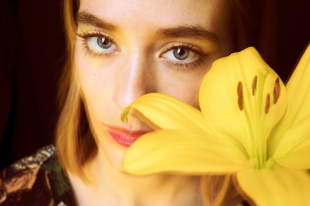 Thoughtful Woman Holding a Yellow Flower – Free to Download