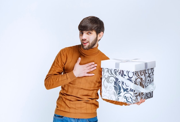 Surprised Man Pointing at White Gift Box with Blue Patterns – Free Stock Photo for Download