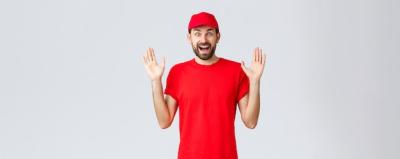 Happy Cheerful Courier in Red T-shirt and Cap Against Grey Background – Free Stock Photo for Download