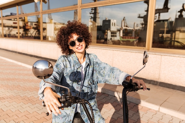 Smiling Curly Woman in Sunglasses on a Motorbike – Free Stock Photo, Download for Free