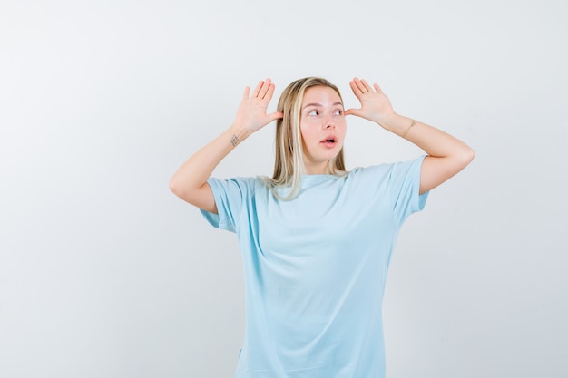 Blonde Girl in Blue T-Shirt with Hands Near Head – Free to Download