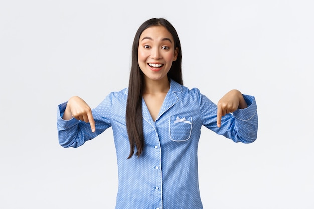 Cheerful Smiling Asian Girl in Blue Pajamas Sharing Exciting News at a Sleepover – Free Download