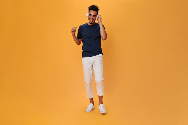 Portrait of a Stylish Man in White Pants Dancing to Music with Headphones – Free Stock Photo for Download