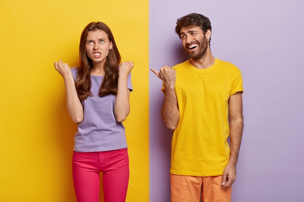 Pleased Guy Enjoys Bright Yellow T-Shirt While Pointing at Irritated Girlfriend – Free Download