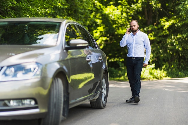 Man Walking Near Car Talking on Cellphone – Free Download