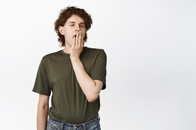 Yawning Male Student with Curly Hair Against White Background – Free Download