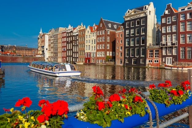 Typical Dutch Dancing Houses and Tourist Boats on Amsterdam’s Damrak Canal – Free Download