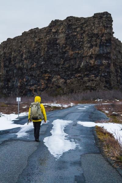 Hiker in a Yellow Jacket Walking on a Scenic Road in Iceland – Free Download