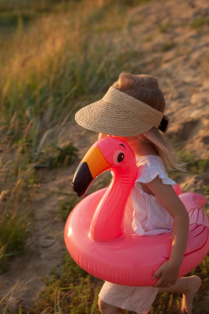 Young Child Enjoying a Pink Flamingo Pool Float at the Beach During Golden Hour – Free Stock Photo, Download Free