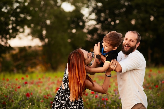 Mom and Dad Embrace Their Little Son in a Poppy-Filled Green Field – Free Download