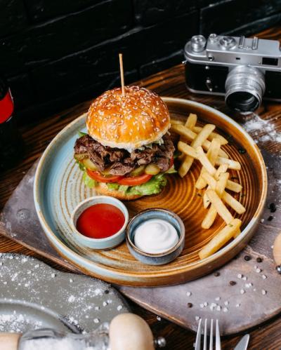 Side View of Burger with Beef, Pickles, and Tomatoes Served with French Fries and Sauces – Free Stock Photo for Download