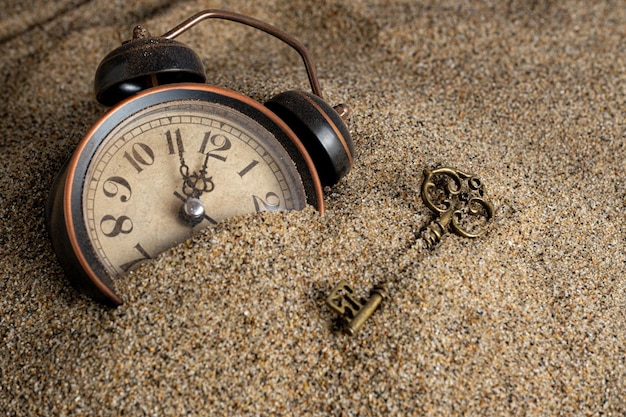 Time Management Concept: Vintage Alarm Clock and Key in Sand – Free Download