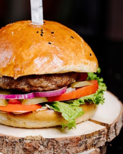 A Delicious Burger in a Bread Bun with Knife on a Wooden Surface – Free Download