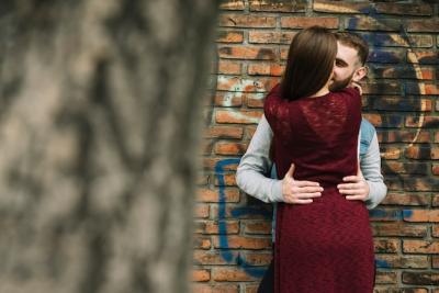 Young Couple Embracing in Front of a Brick Wall – Free Download